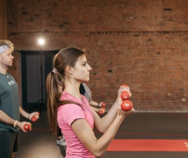 Group of adults exercising indoors with dumbbells, focused on fitness and health.